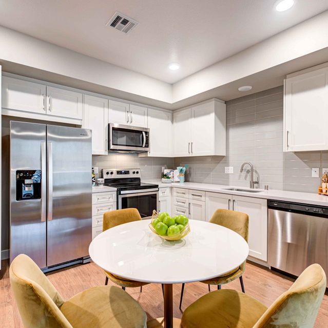 Two Bedroom Apartments in Redlands, CA - The Summit - Kitchen With White Cabinetry, Stainless Steel Appliances, White Tile Backsplash, and Wood-Like Flooring Throughout