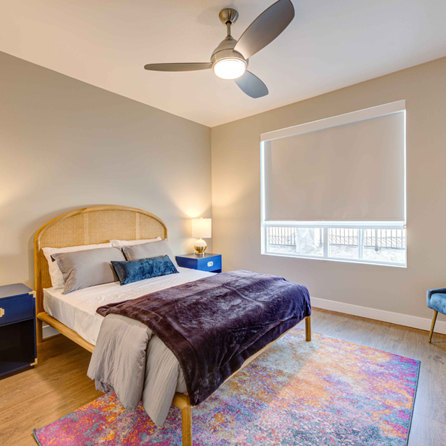 Apartments for Rent in Redlands, CA- The Summit - Spacious Bedroom with Wood-like Flooring, Large Windows, High Ceilings with Ceiling Fan, Furnished with Bed, Side Tables, and Dresser
