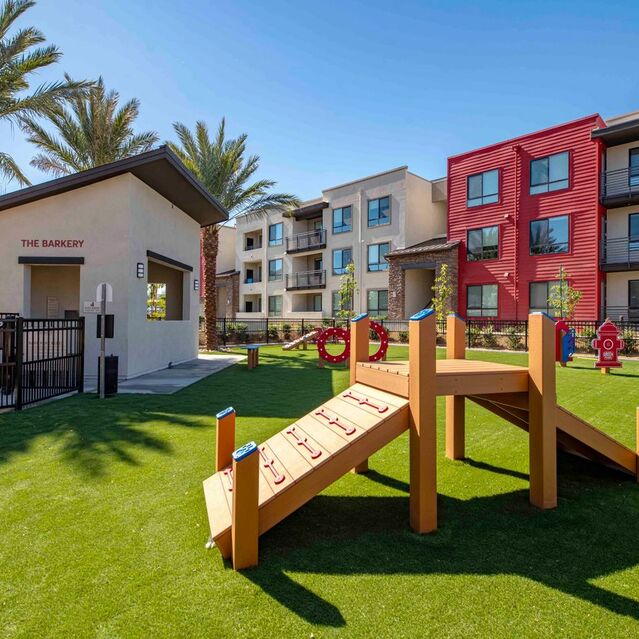 Pet-Friendly Apartments in Redlands, CA - The Summit - Dog Park With Grass Turf, Pet Waste Station, Agility Equipment, Lush Landscaping, and Red Garden Patio Chairs Fitness Center