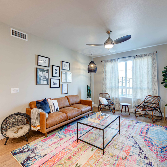 One Bedroom Apartments in Redlands, CA - The Summit - Living Room With Open Layout, Large Windows, High Ceilings with Ceiling Fan, and Wood-Like Flooring